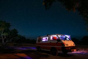 A campervan parked under a starry night sky in the Australian outback, offering a tranquil nature adventure.